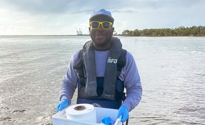 a man stands in water holding a plastic container